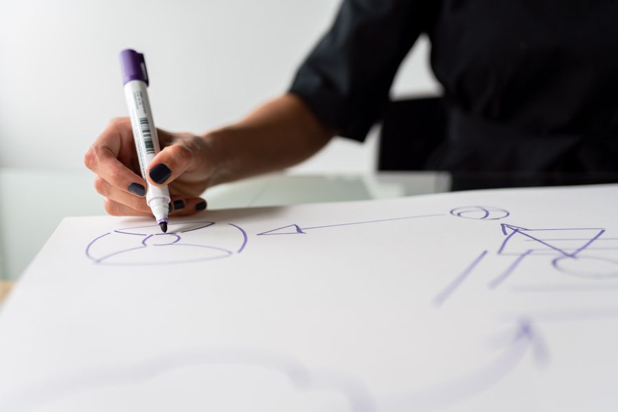 A hand sketching a plan on paper, the early creative planning stage of building an app
