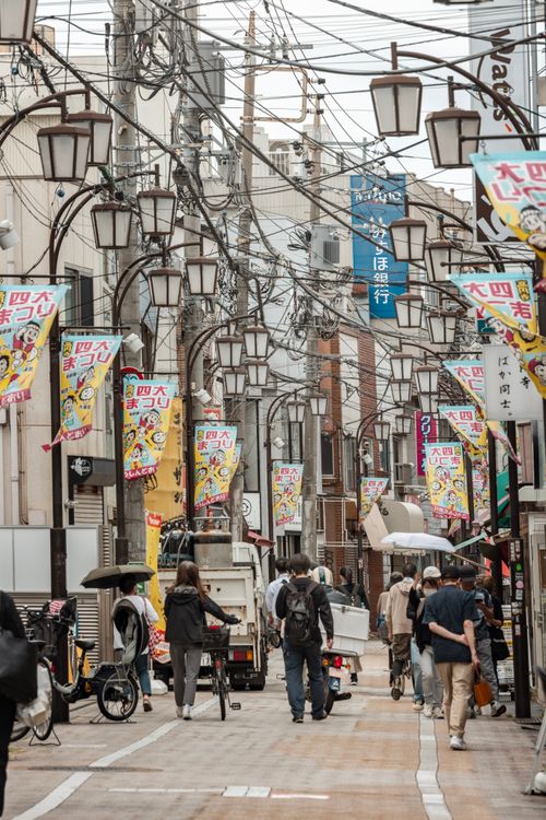 Free Bustling Tokyo street with colorful banners and people walking on a cloudy day. Stock Photo