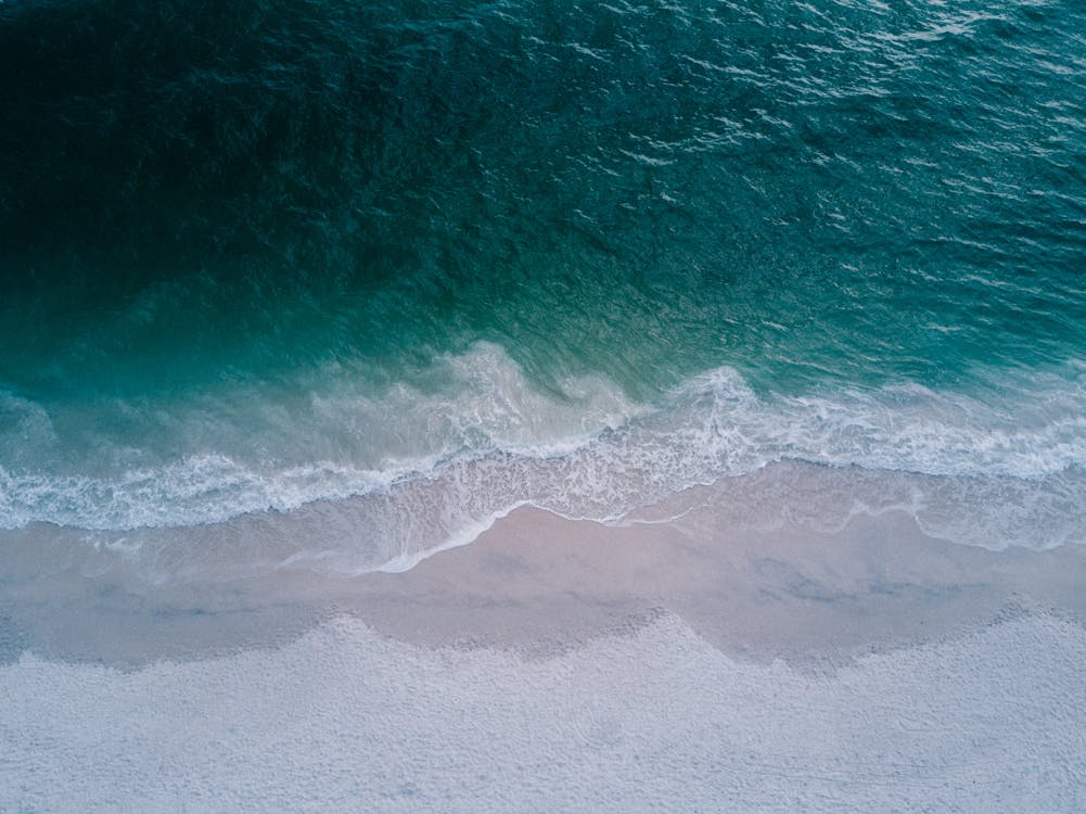 Body of Water Beside Beach Sand