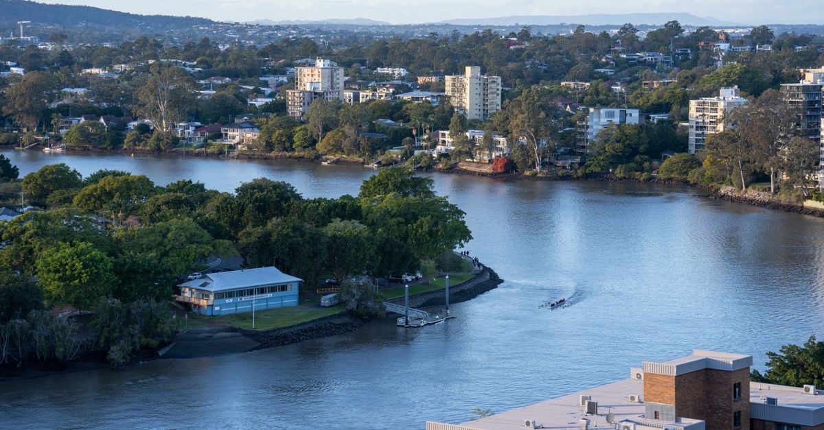 A beautiful aerial view of the Brisbane River with lush greenery and city buildings at dusk.