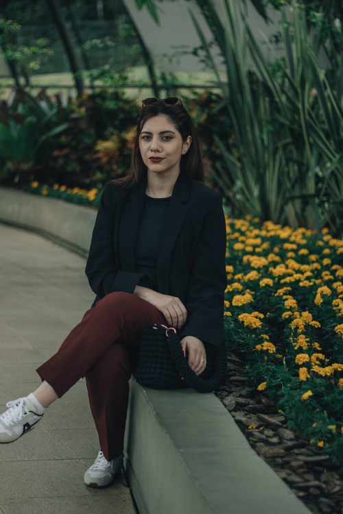 Free Woman seated in a botanical garden, surrounded by lush greenery and flowers. Stock Photo