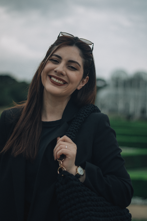 Free Cheerful woman with sunglasses smiling in a garden setting. Stock Photo