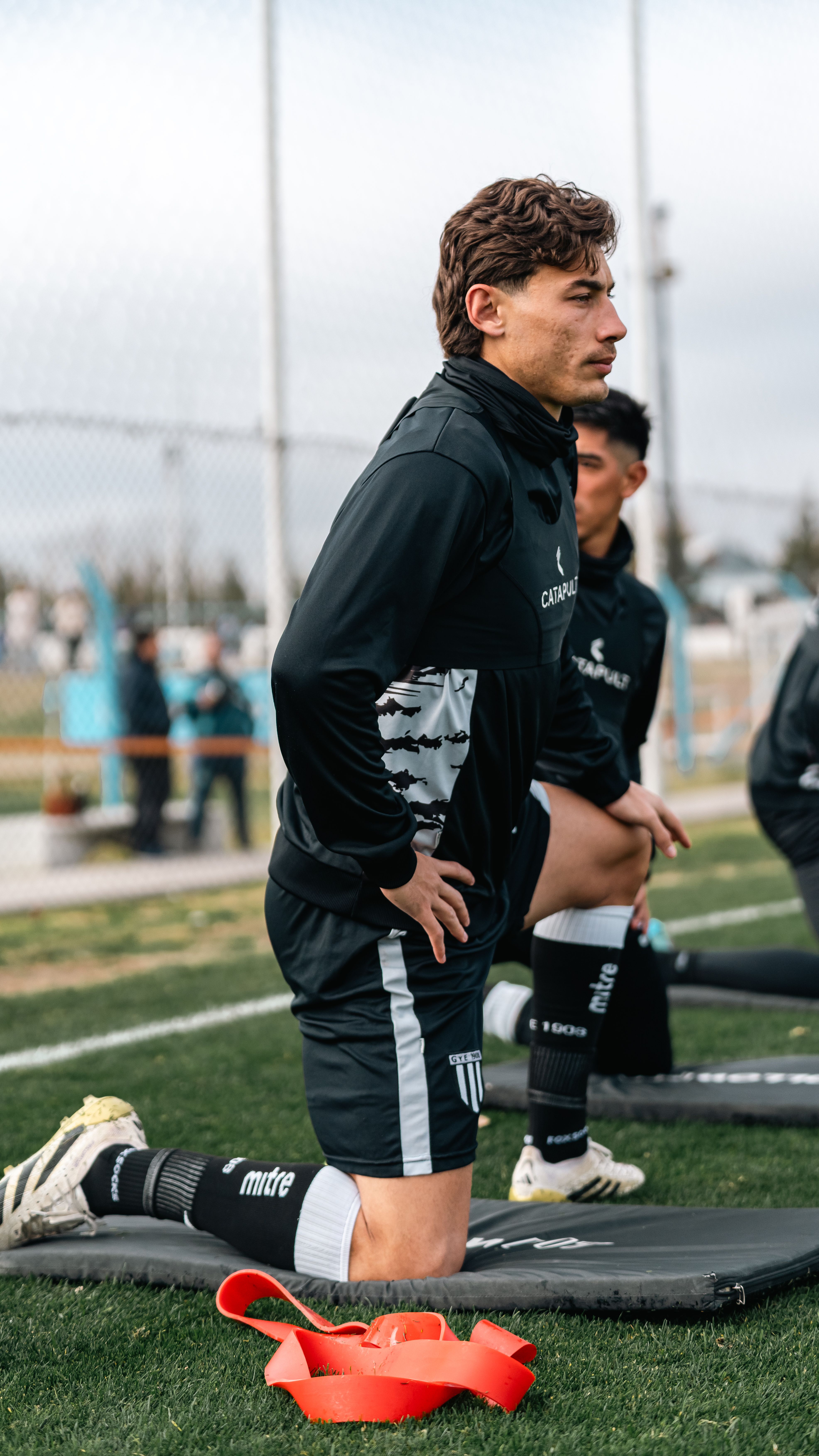 Two young male soccer players warming up outdoors on a field, preparing for a game.