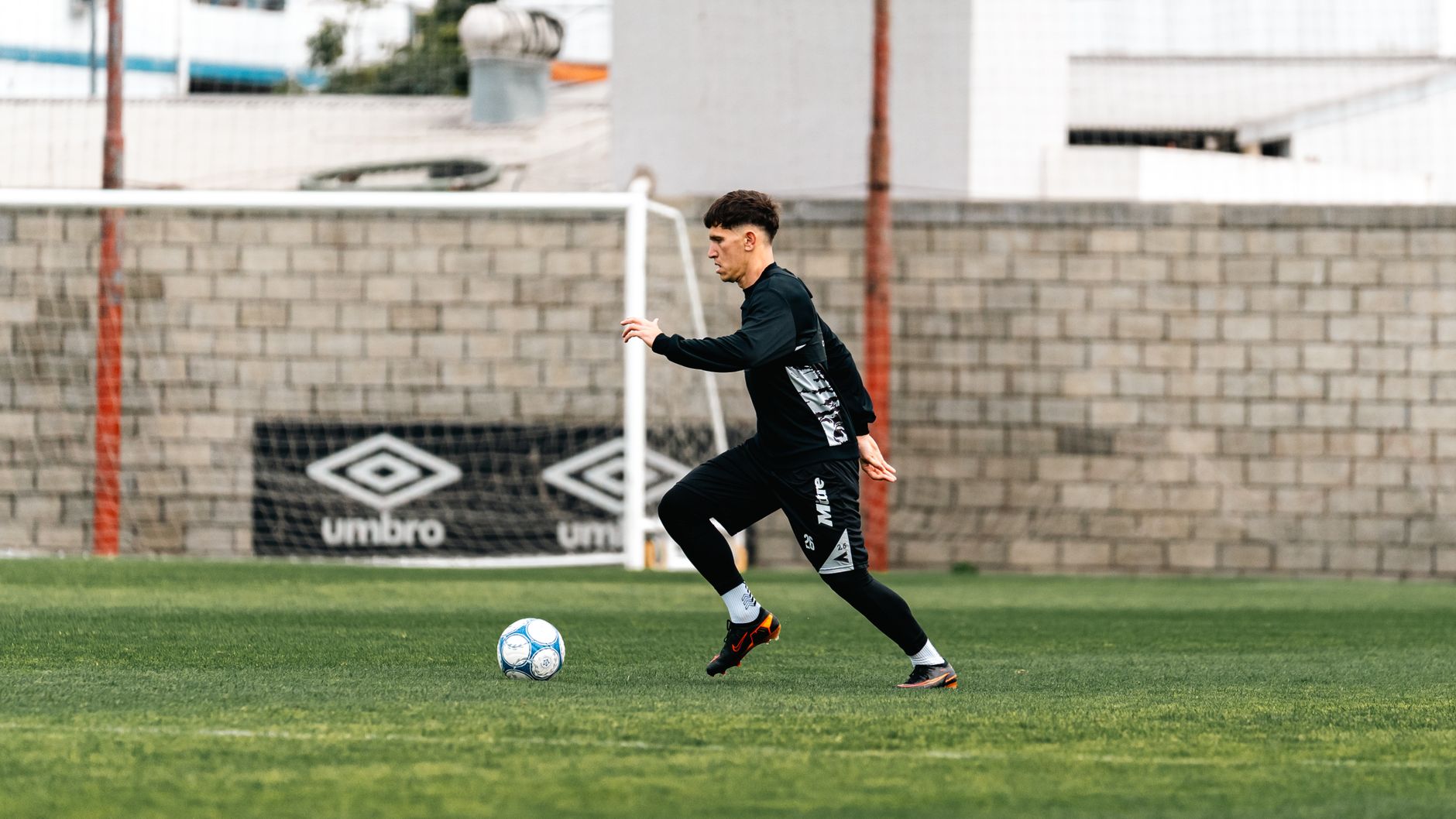 Youth soccer player in dynamic action on an outdoor field, showcasing skills and athleticism.