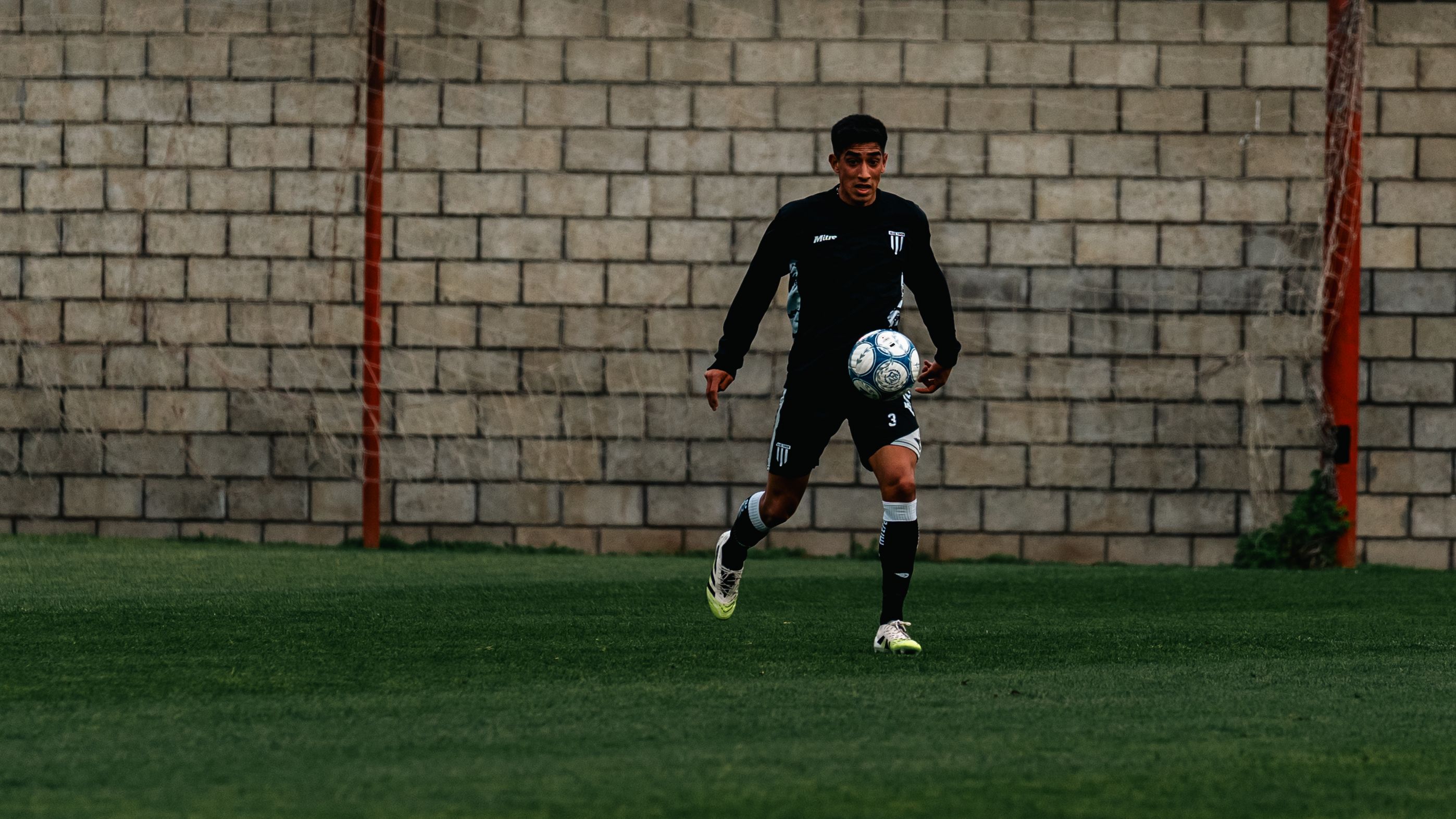 Siyah formasıyla antrenman sırasında top süren bir futbolcu.
