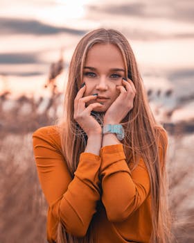 日落时分，一位留着金色长发的年轻女子双手放在脸上