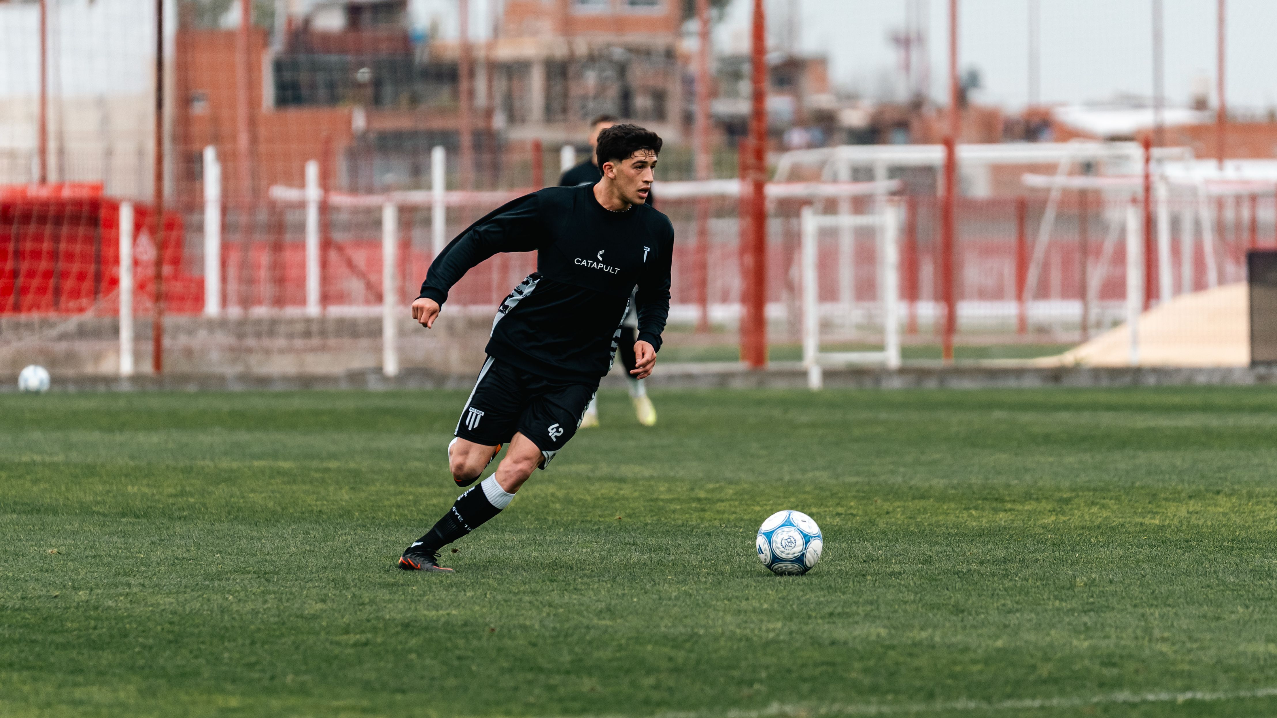A soccer player in action dribbling the ball during a game on an outdoor sports field.