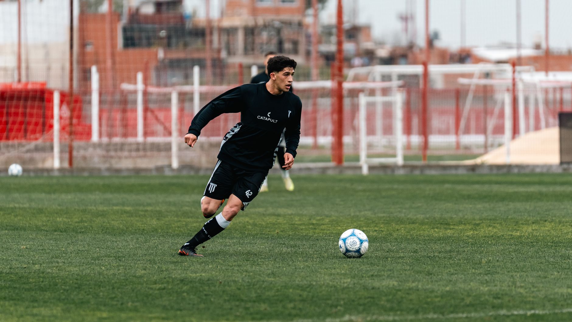 A soccer player in action dribbling the ball during a game on an outdoor sports field.