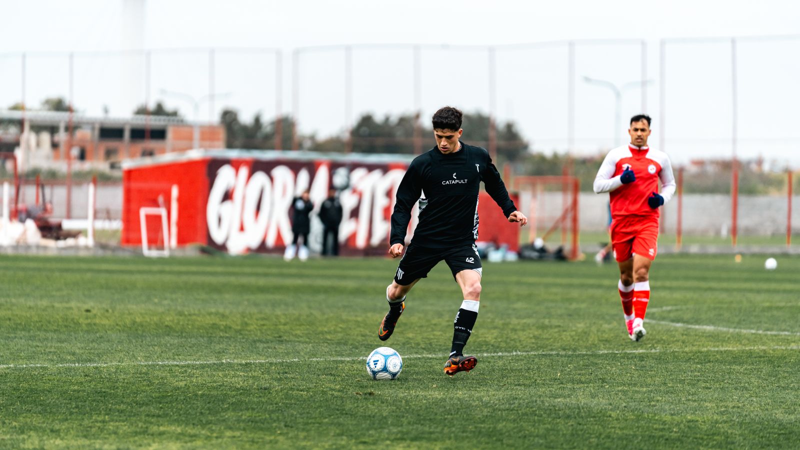 Action shot of soccer players practicing on an outdoor field, highlighting movement and sportsmanship.