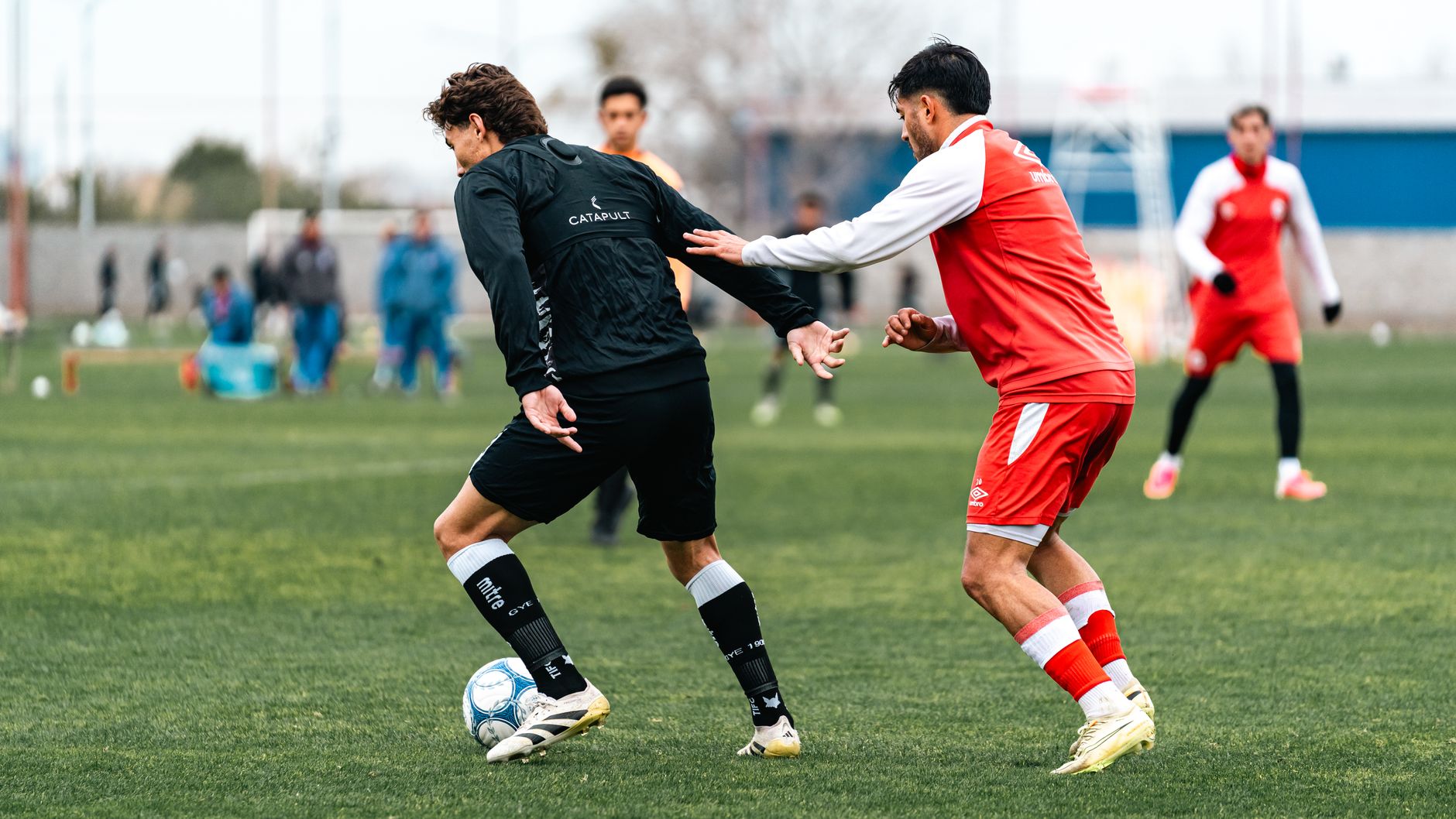 coach demonstrating defensive transitions with magnets on a green soccer tactics board beside match footage