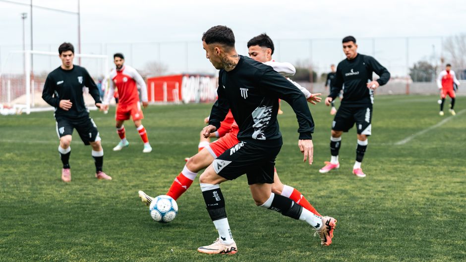 Dynamic soccer match with players in black and red jerseys engaged in a game on a green field.