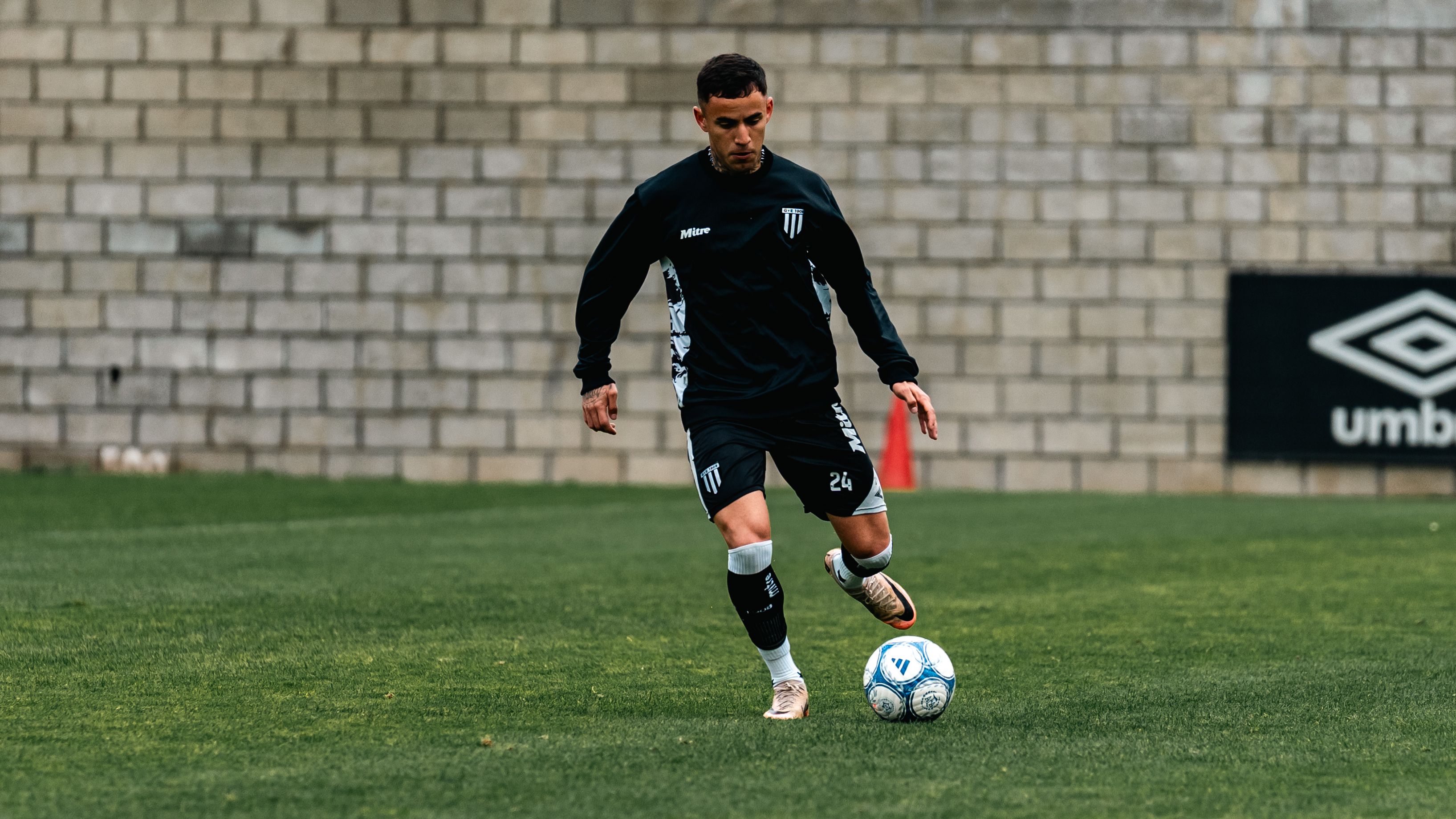 A midfielder cushioning a fast wall pass with the inside of the foot during an early morning training session