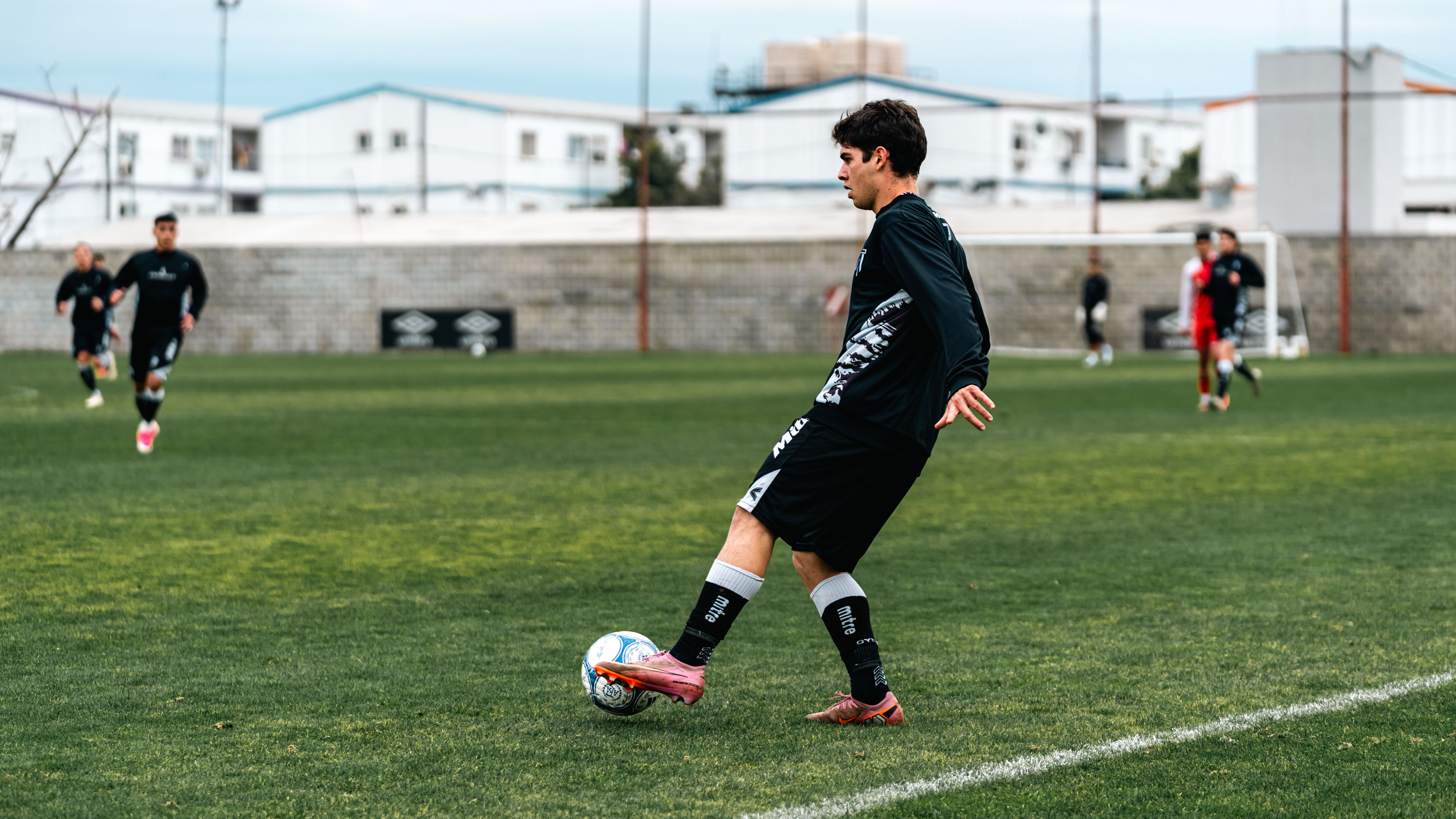 Footballer controlling a high pass near a concrete wall during focused evening practice