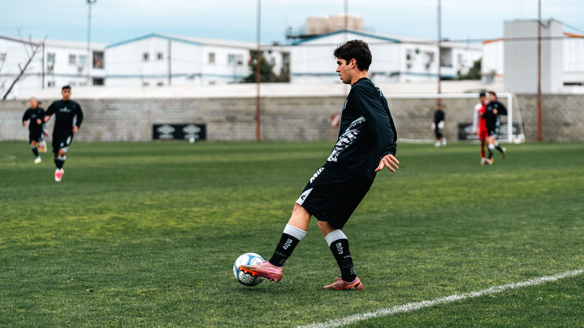 Footballer controlling a high pass near a concrete wall during focused evening practice