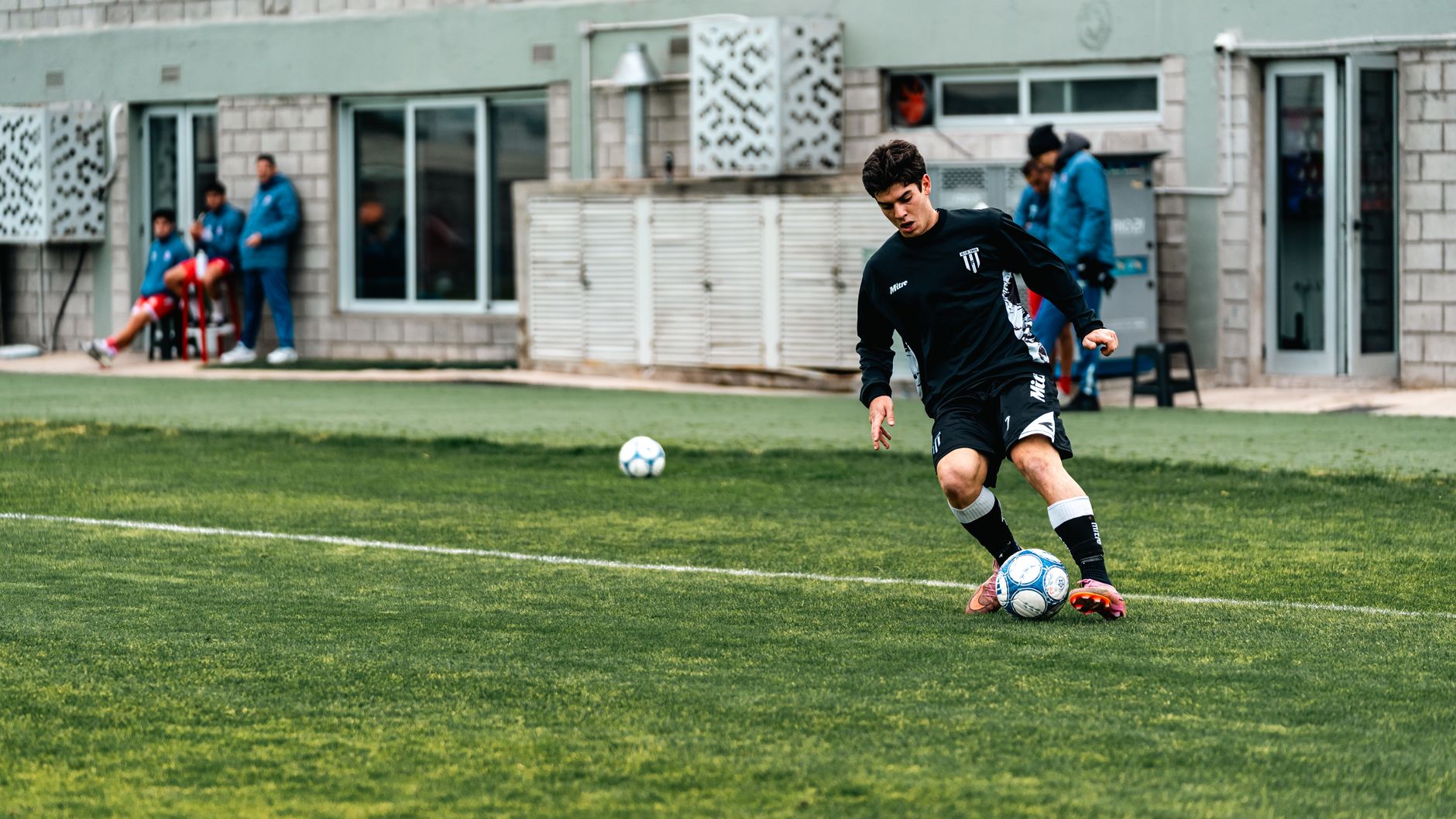 winger attacking a fullback during a competitive one-on-one football drill under bright stadium floodlights