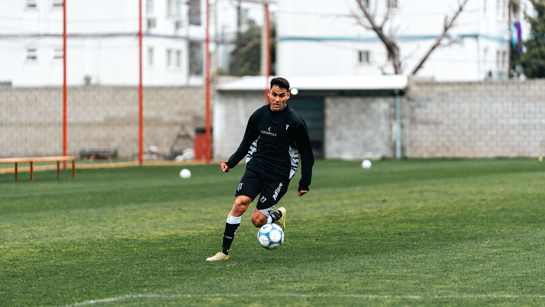 football player performing sprint intervals on a marked training pitch at sunrise, focused and exhausted