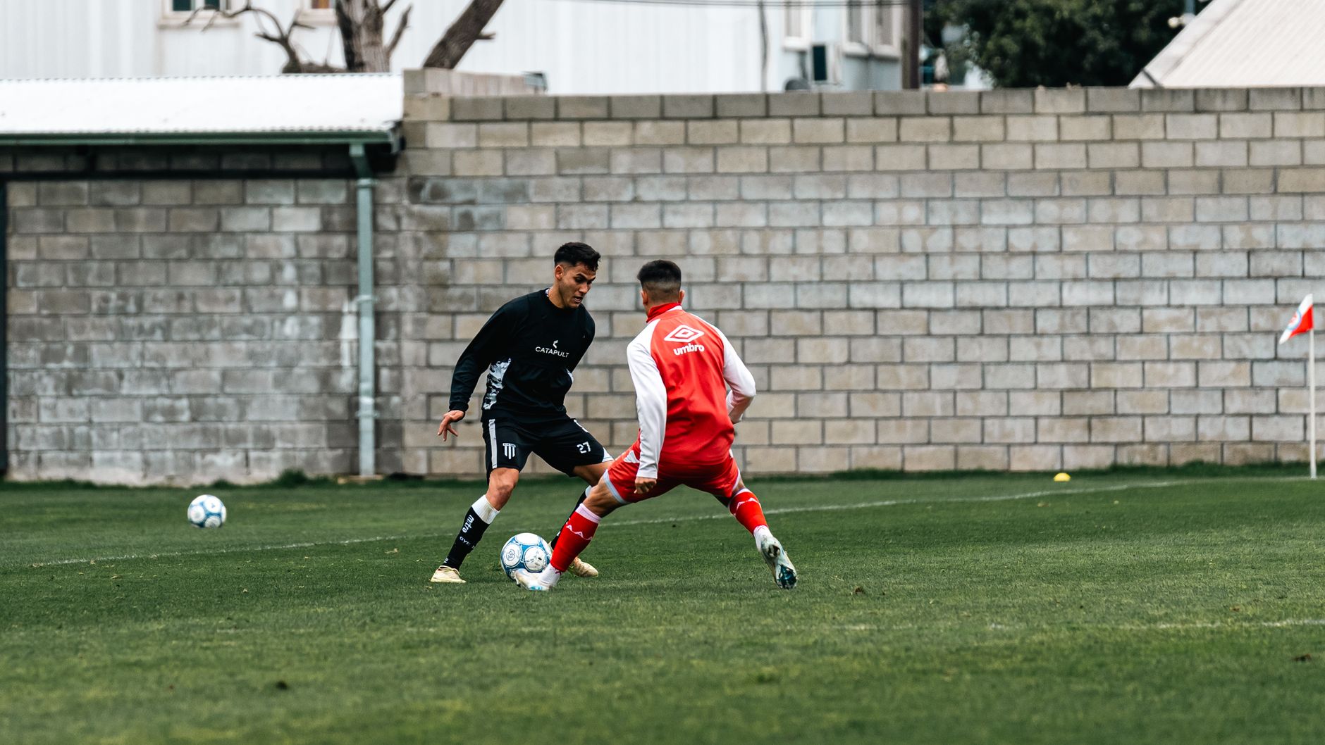 Two male soccer players in action on a grass field during the day.