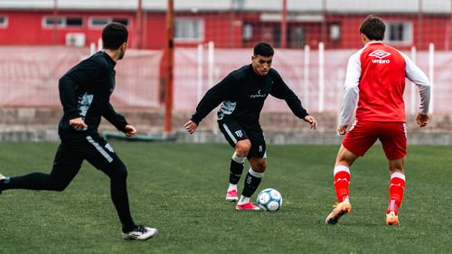 Free Three young men engaged in a competitive soccer practice on a grassy field. Stock Photo
