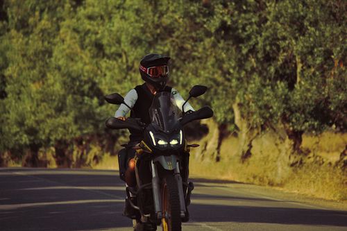 Free Motorcyclist cruising on a forest road, embodying freedom and adventure. Stock Photo