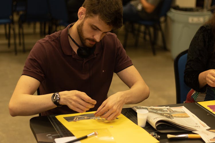 Attentive Young Male Student Creating Scrapbook In Classroom