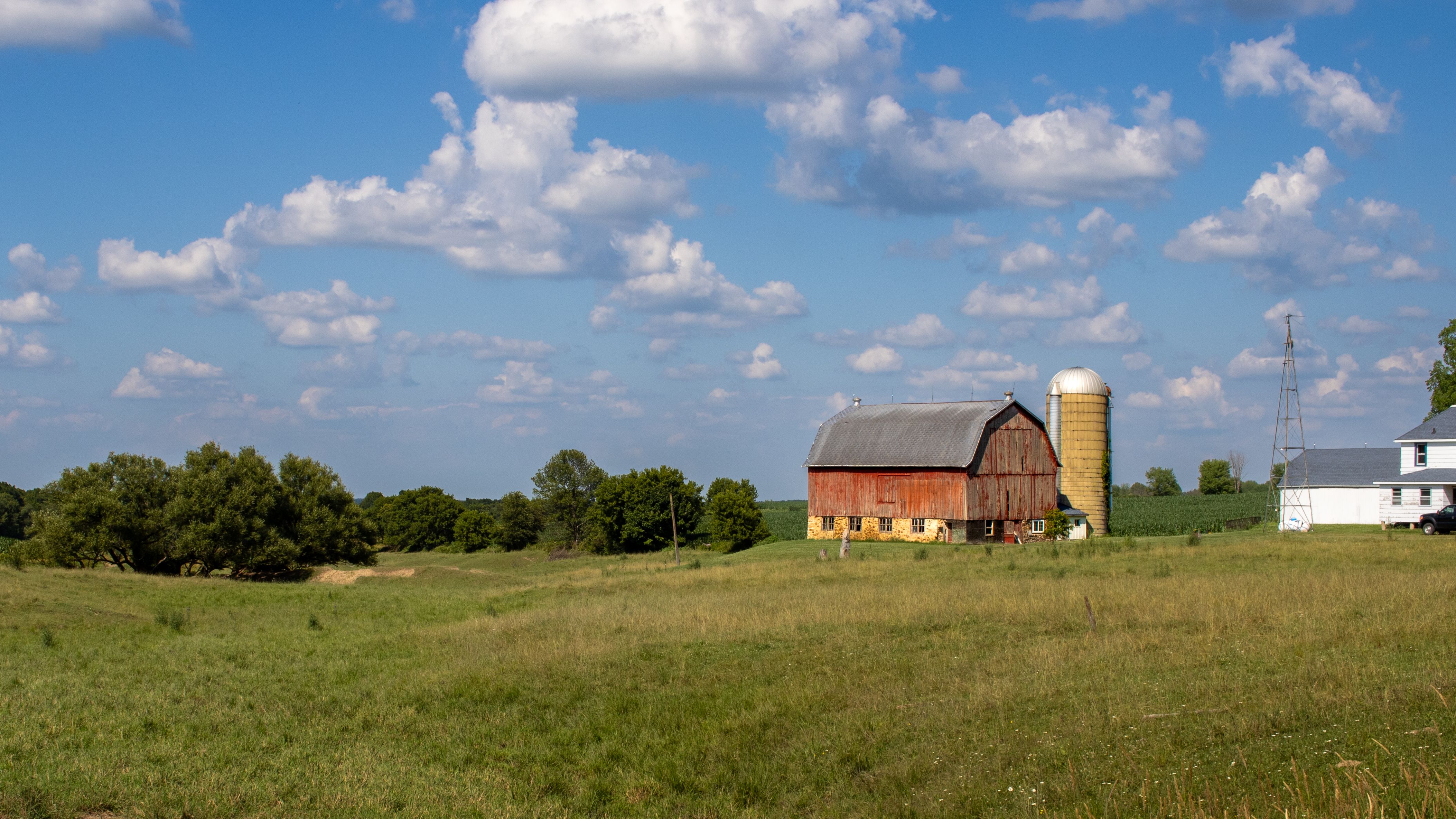 Red barn and silo under a bright sky on a working farm
