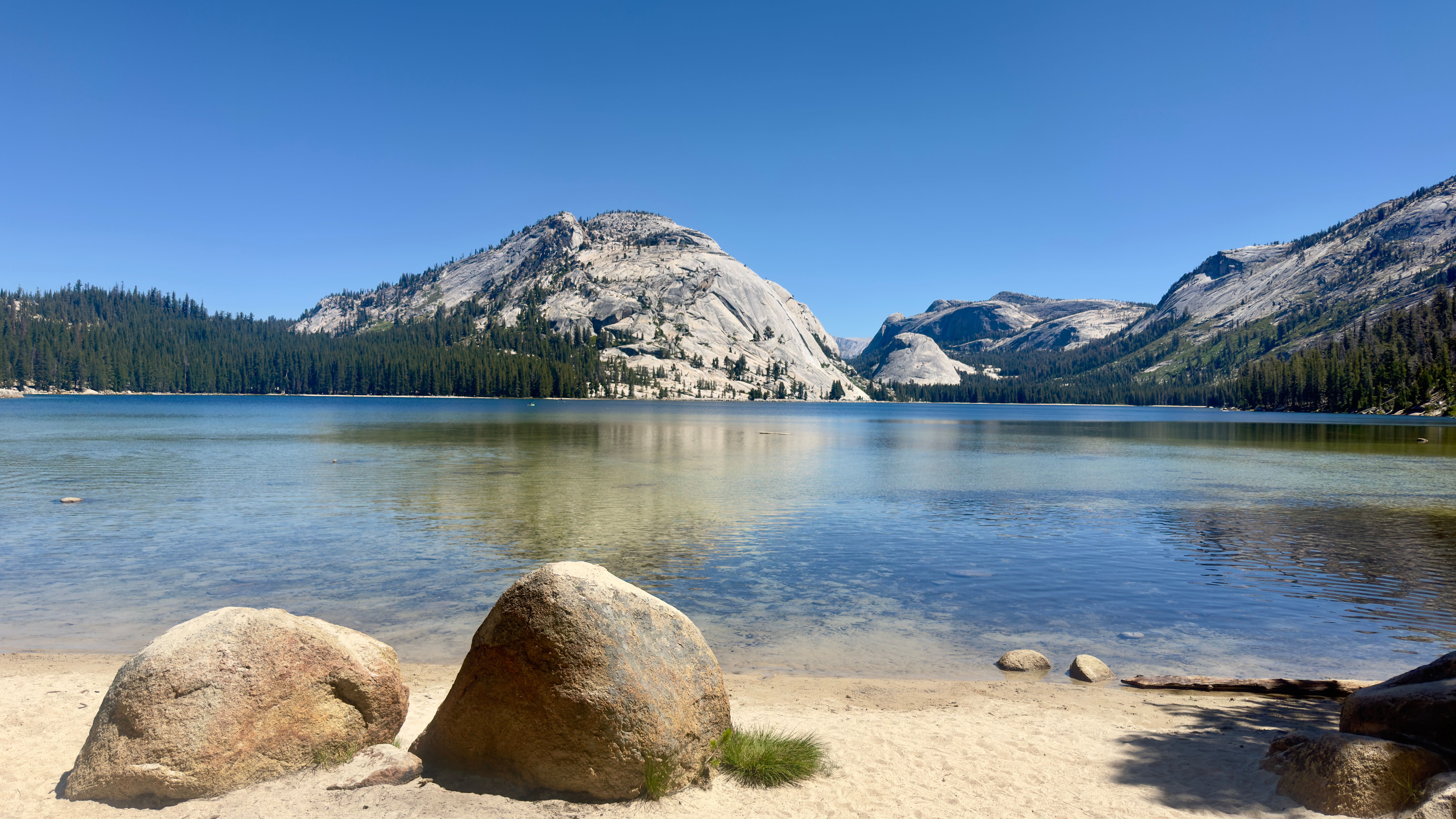 Breathtaking landscape of Tenaya Lake in Yosemite, surrounded by majestic mountains and clear skies.