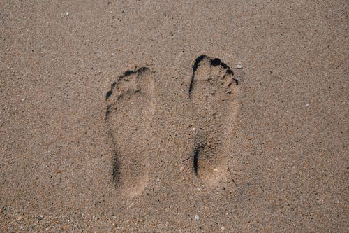 Free Close-up of two footprints in sand, evoking summer beach vibes. Stock Photo
