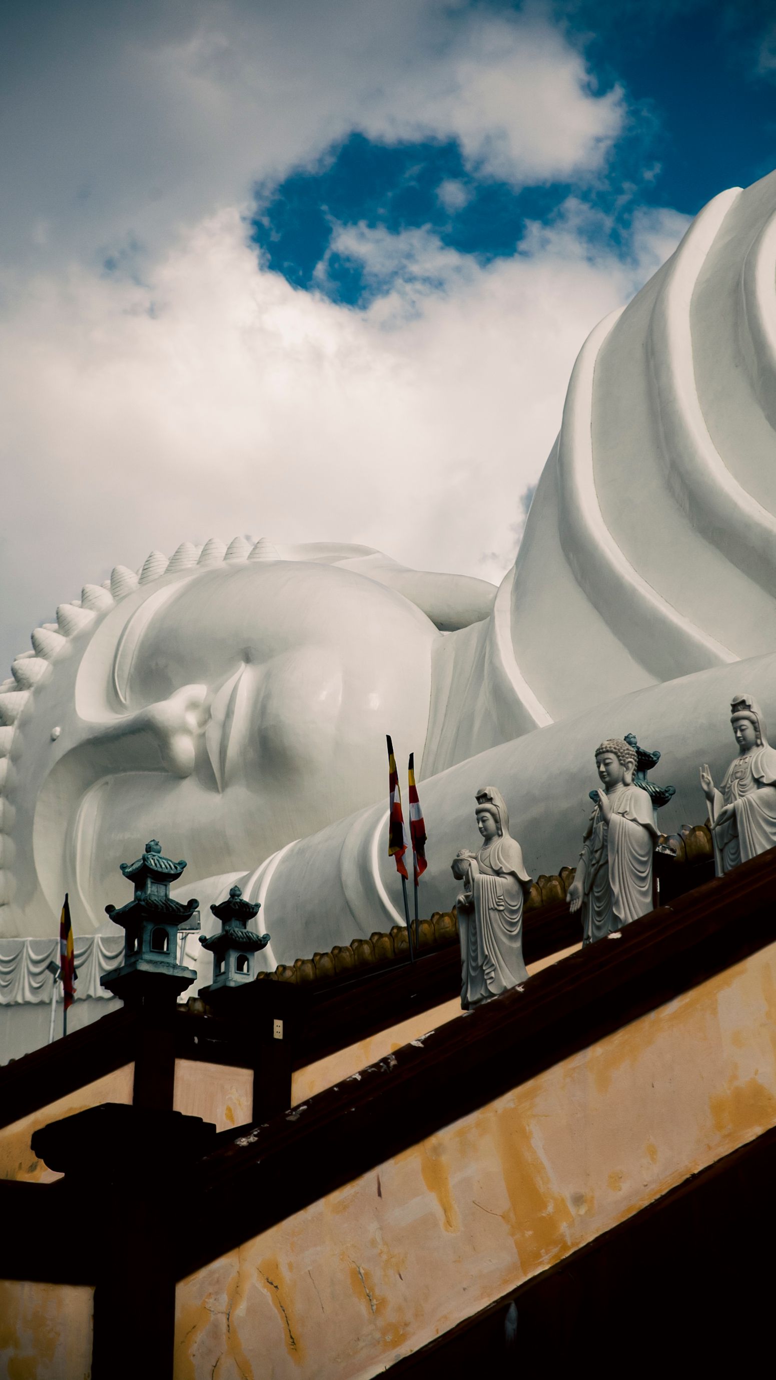 A serene view of the giant reclining Buddha statue at Vinh Trang Pagoda under a cloudy sky.