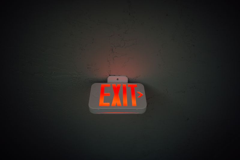 Illuminated exit sign hanging from a building ceiling