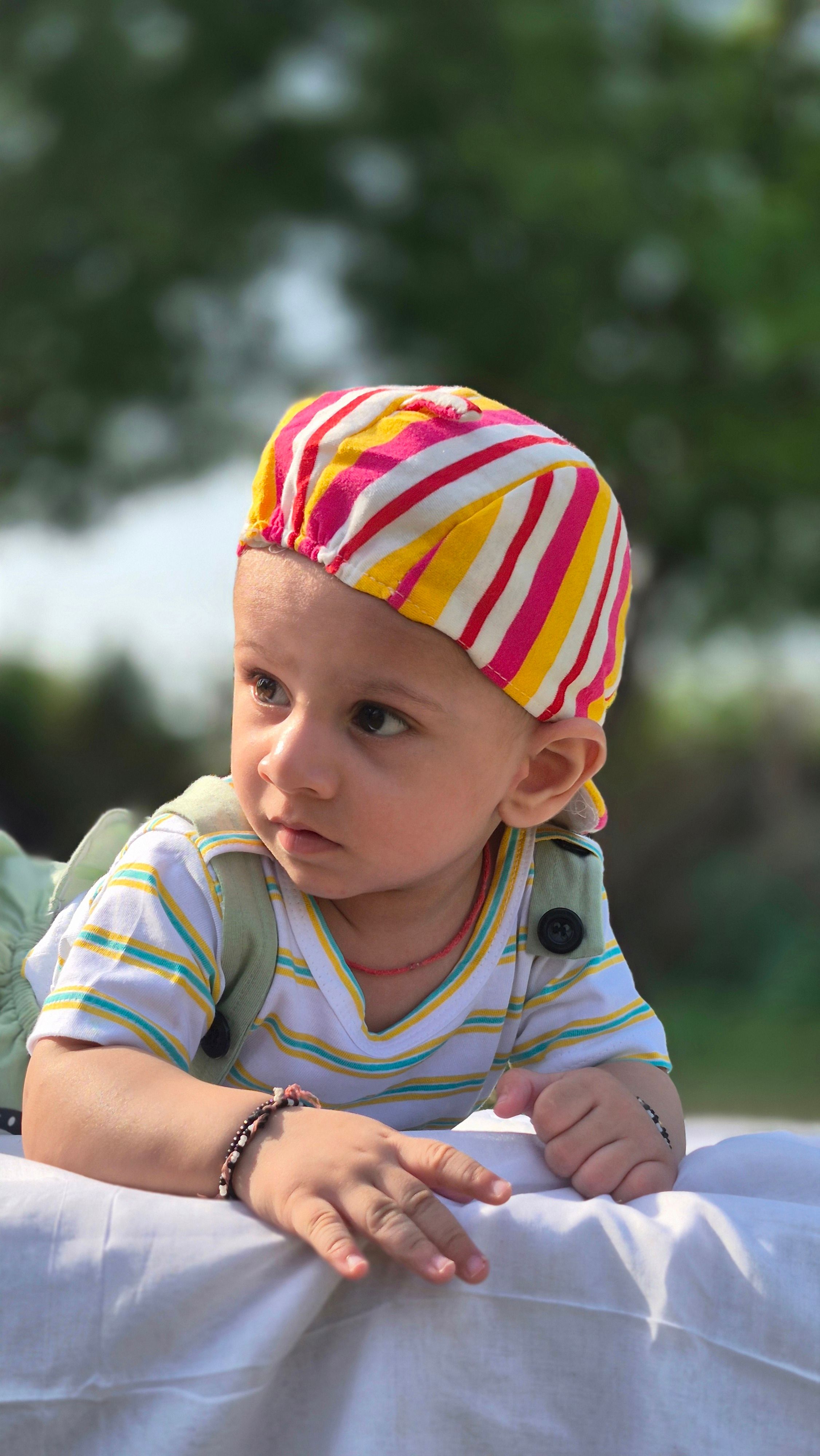 Charming baby wearing a colorful hat, enjoying an outdoor day in Rajasthan.