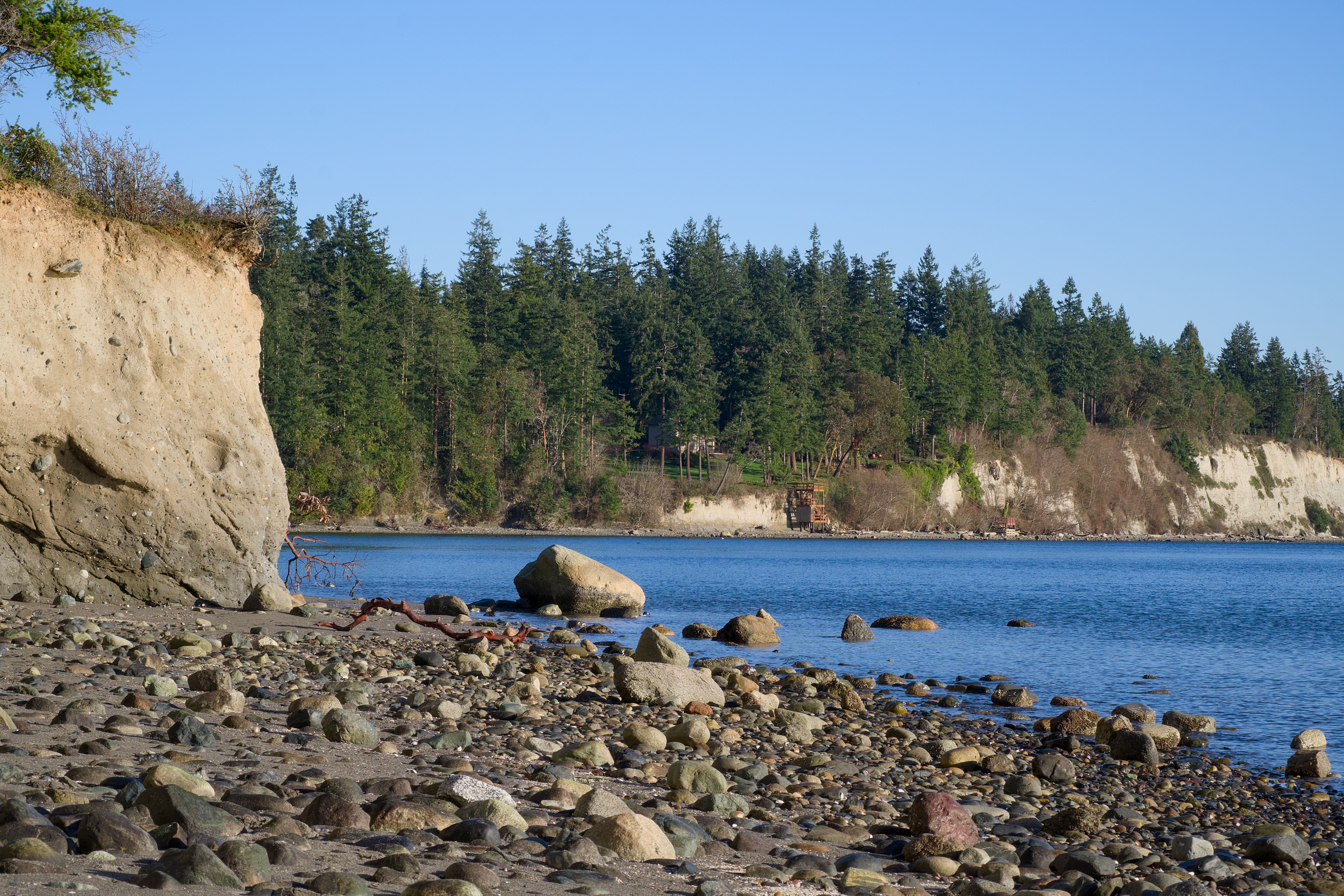 Idyllic coastal scene in Hansville, Washington with beach, cliffs, and evergreen trees.