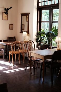 Warm and inviting cafe interior in Vietnam with wooden furniture and natural light streaming through large windows.