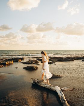 A bride in a white dress walks along a serene beach at sunset in Antalya, Türkiye.