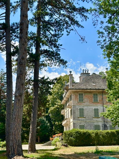 Free A picturesque manor house surrounded by tall trees and vibrant greenery in a serene setting. Stock Photo