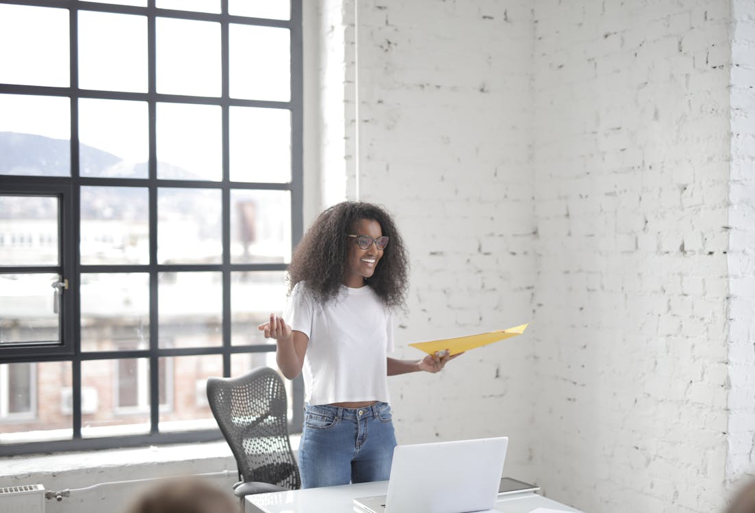 Cheerful young black female speaker presenting ideas at meeting in office workspace