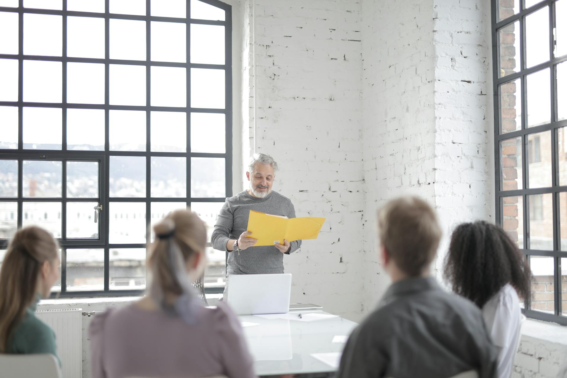 A senior executive leading a team meeting in a bright, modern office setting.