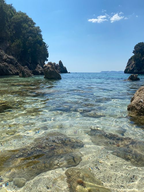 Free Pristine clear water in a rocky coastal cove under a bright blue sky. Stock Photo
