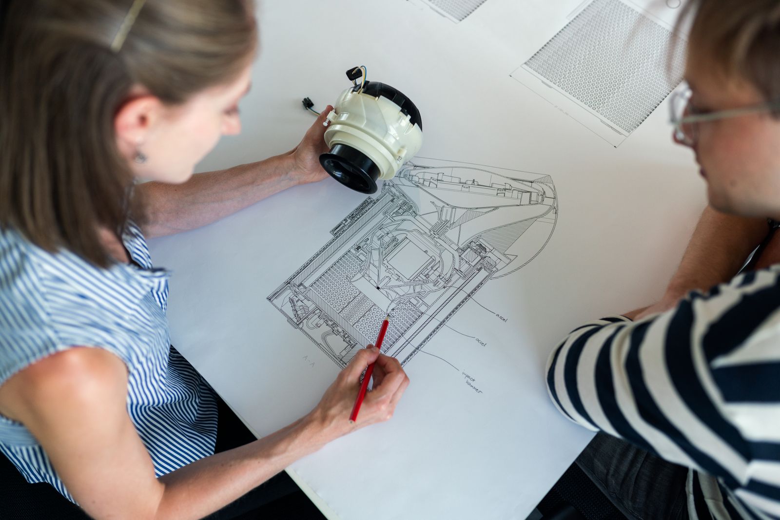 Engineers reviewing a detailed product drawing during design planning
