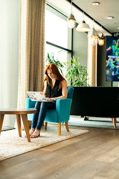 一名年轻女子在光线充足的现代休息室里用笔记本电脑工作，这正是远程办公的理想环境