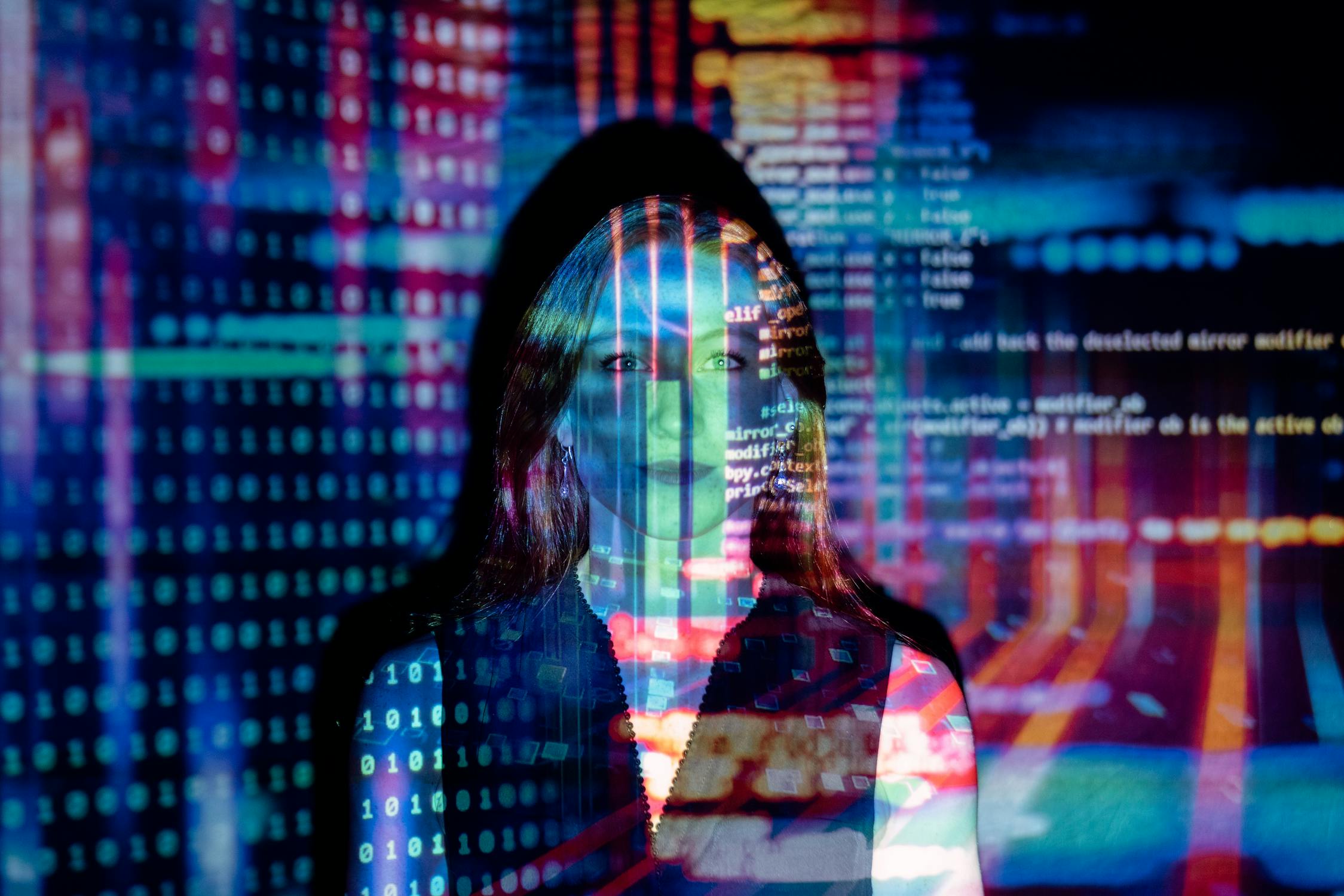 Image of woman overlaid with code and computer hardware images in different colors. 