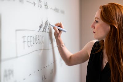 A woman writing on a board for affordable SEO services for small businesses