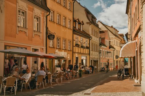 Free Idyllic street in a German old town with cafes and people enjoying outdoor seating. Stock Photo
