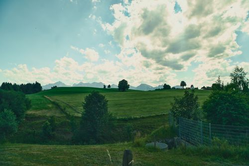 Free Scenic view of Bavarian fields and rolling hills under a vibrant summer sky. Stock Photo