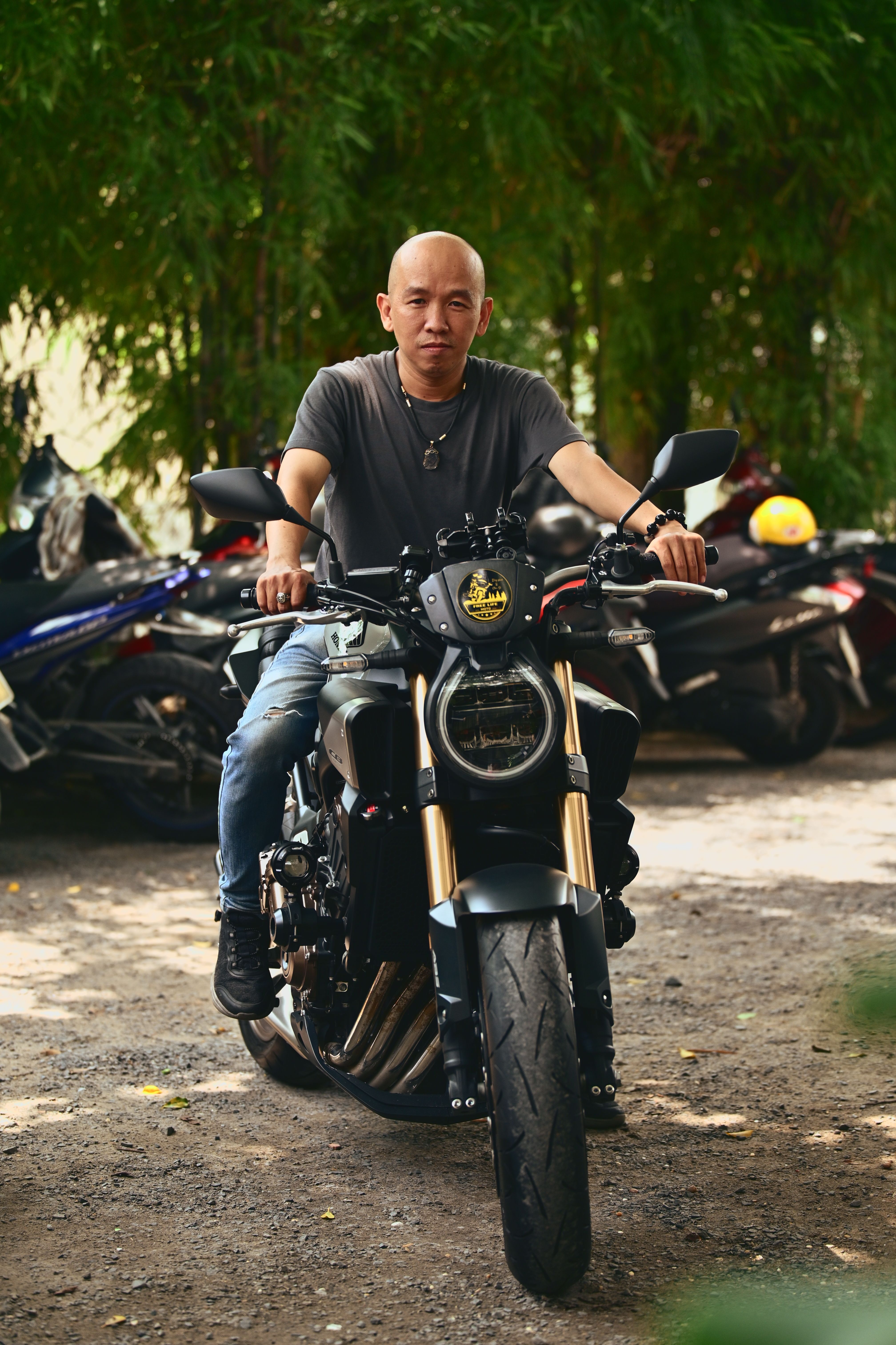 Man riding a motorcycle in an outdoor environment surrounded by foliage.