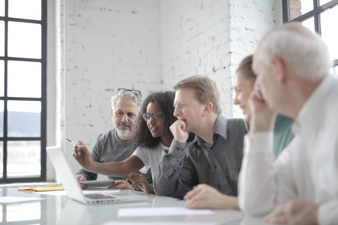 Content multiracial coworkers talking about project and watching laptop