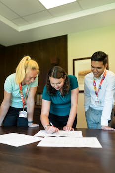 Three colleagues collaborating on a project around an office table, fostering teamwork and cooperation.