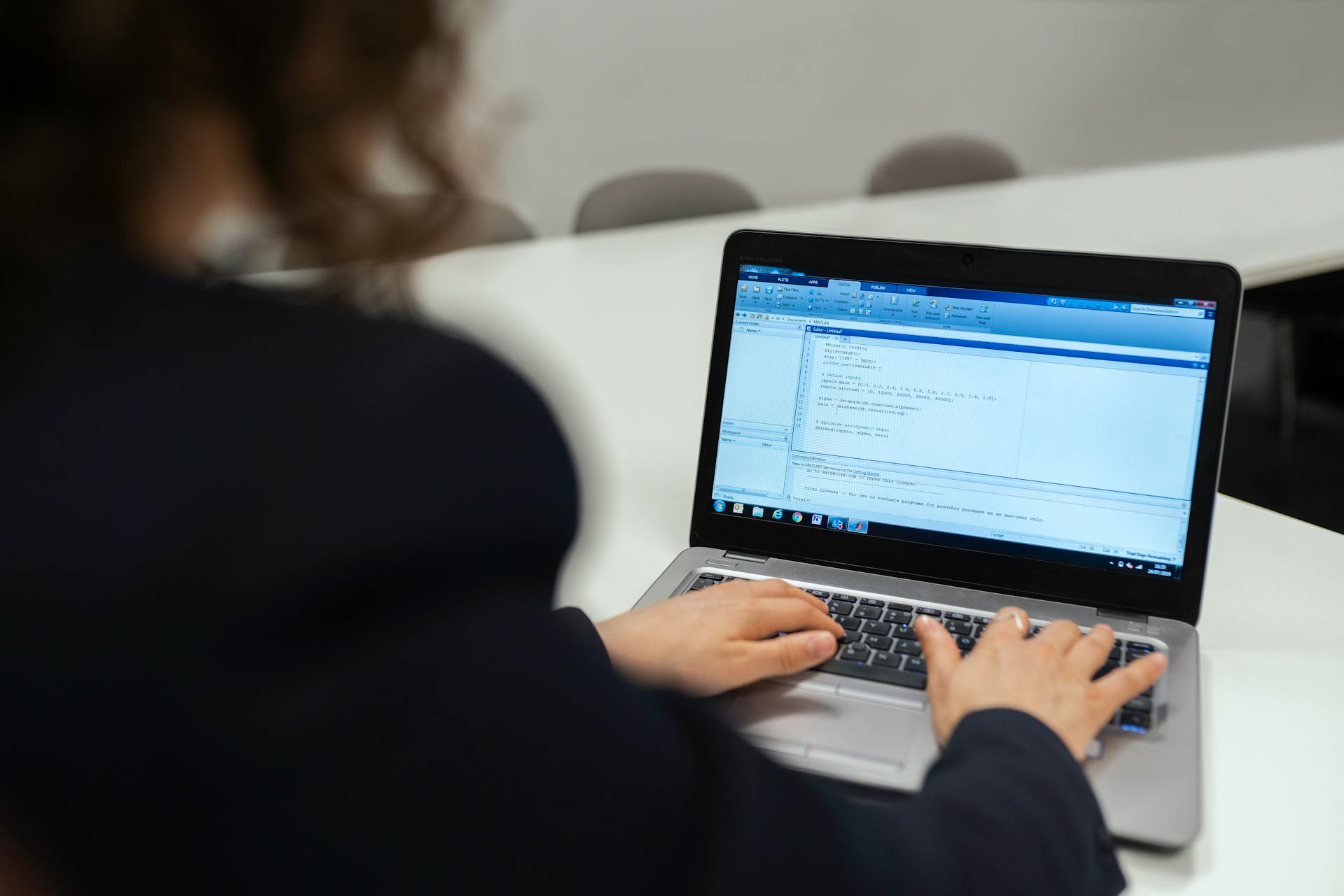 Focused woman coding on a laptop in a modern office setting.