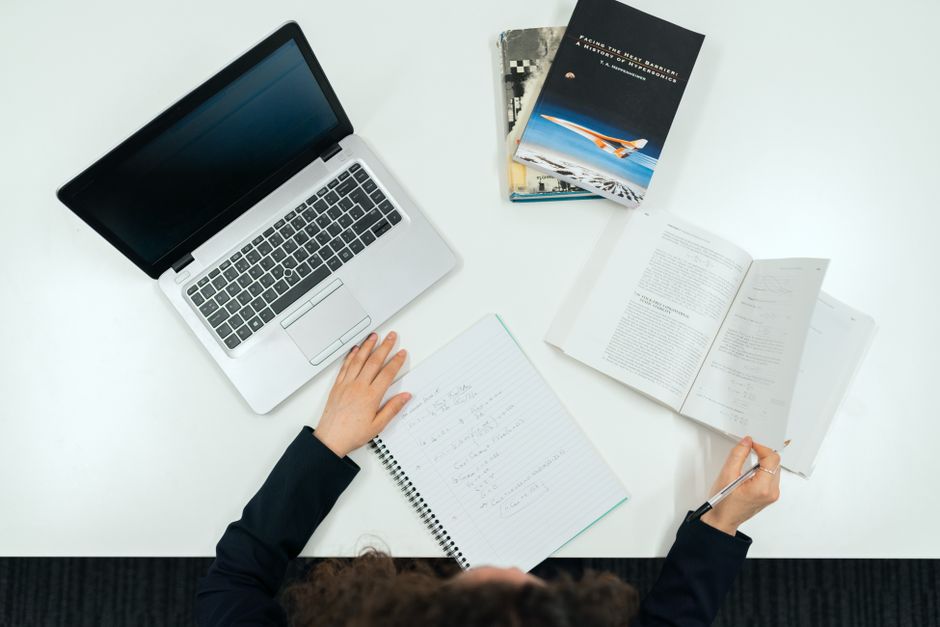 Top view of a work desk with laptop, books, and notes showcasing productivity. Top view of a work desk with laptop, books, and notes showcasing productivity.