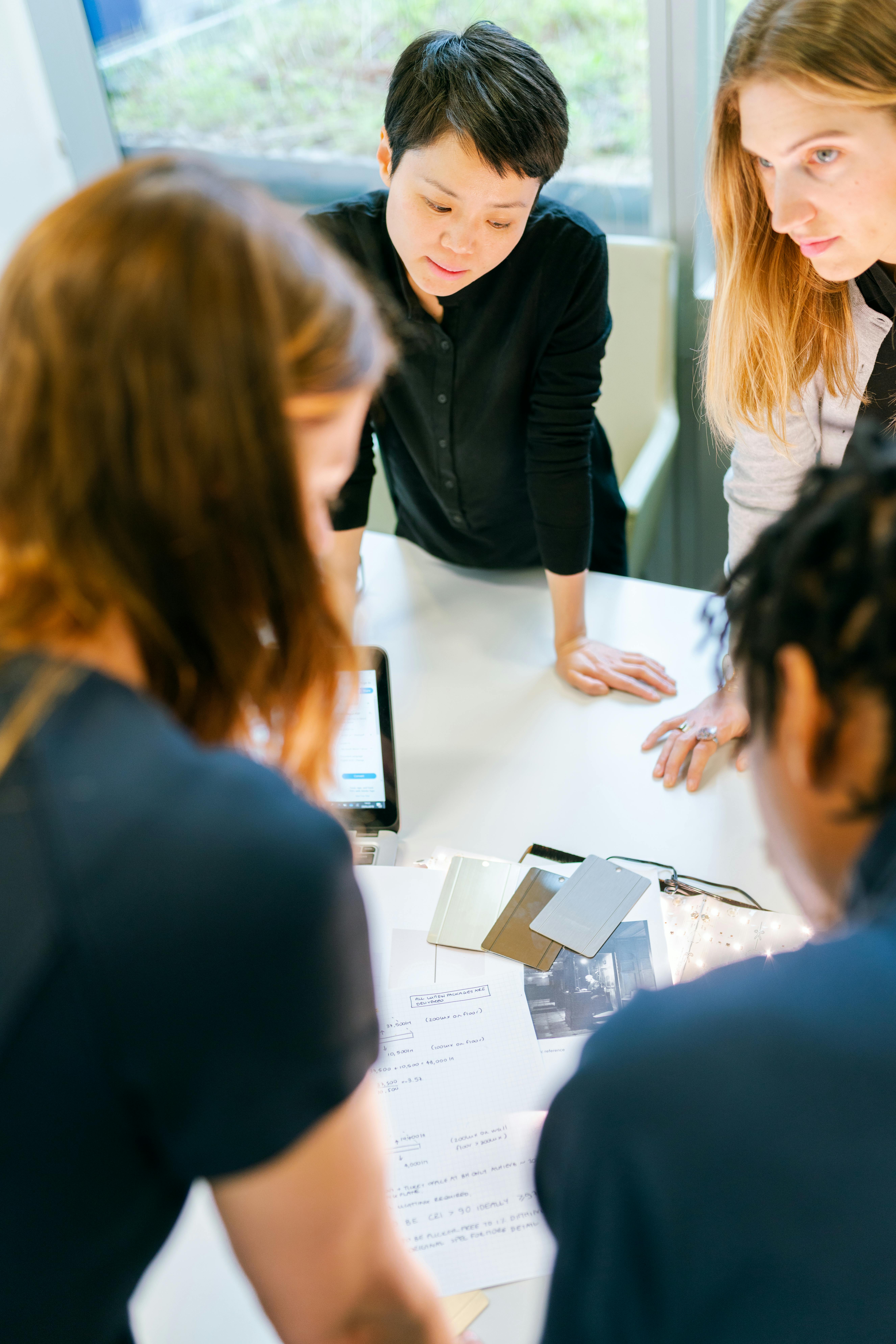 Free A group of adults engaged in teamwork and planning at an indoor office meeting. Stock Photo
