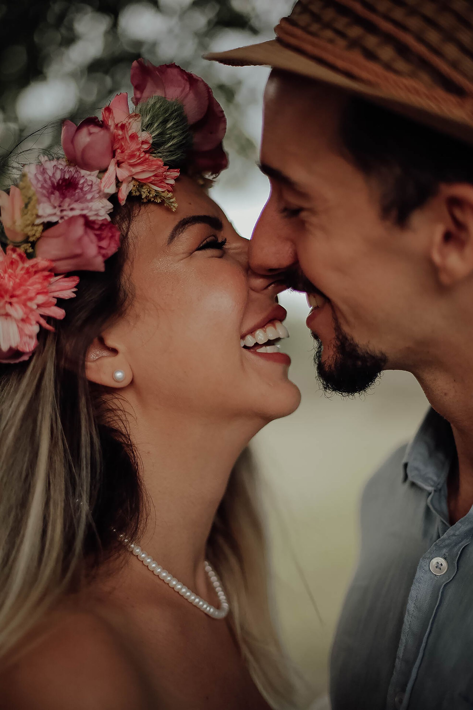 Close-up of a joyful couple sharing a laugh, woman wearing a floral crown.